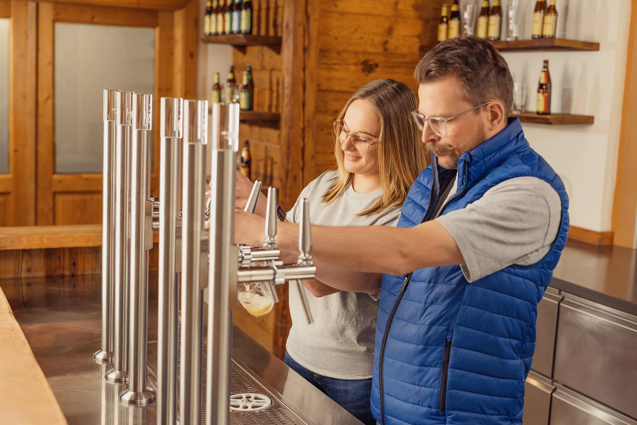 Eine Frau und ein Mann zapfen in der Hirter Bierathek Bier.