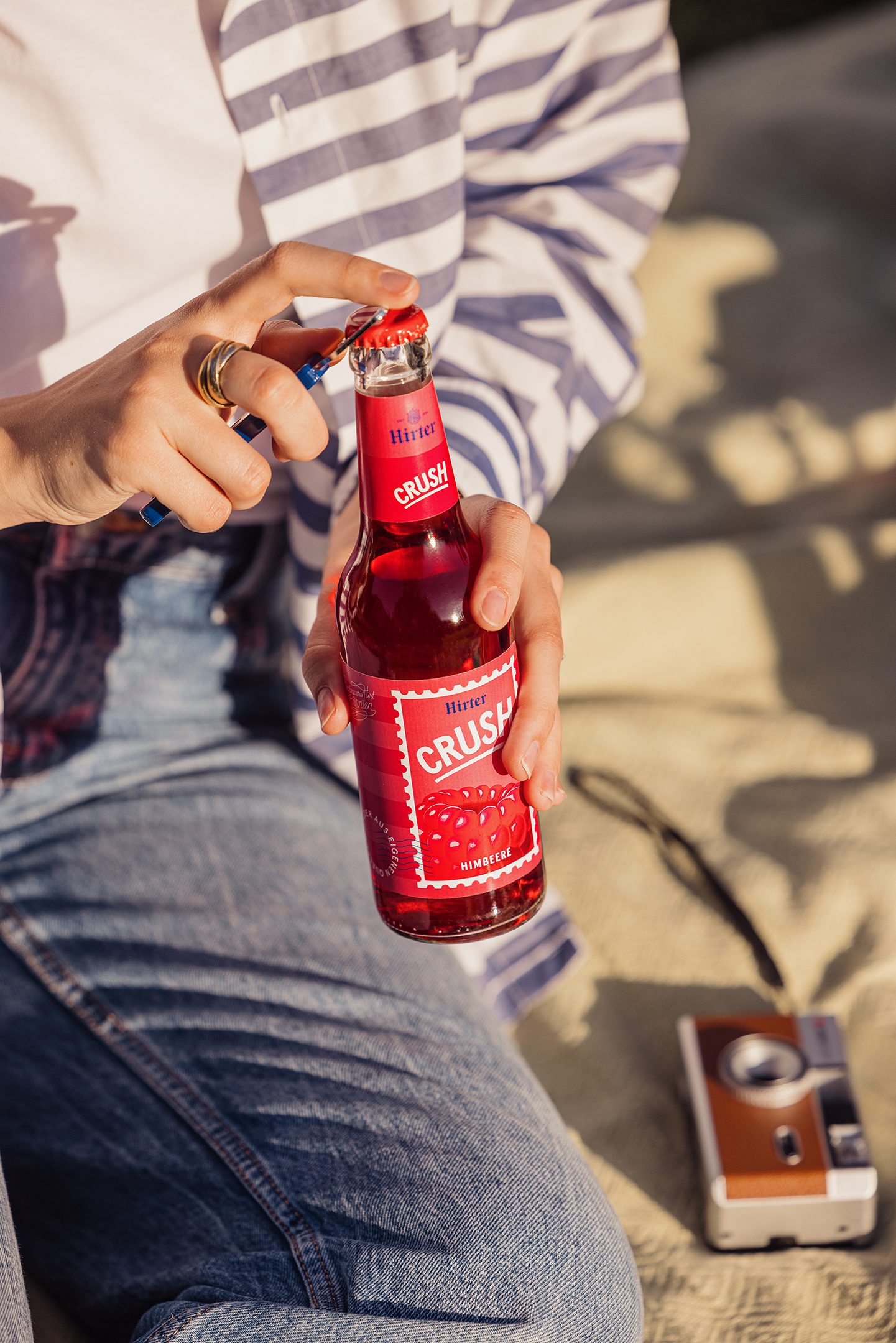 Eine Person hält die Limonade Hirter Crush Himbeere in der Hand und öffnet sie.