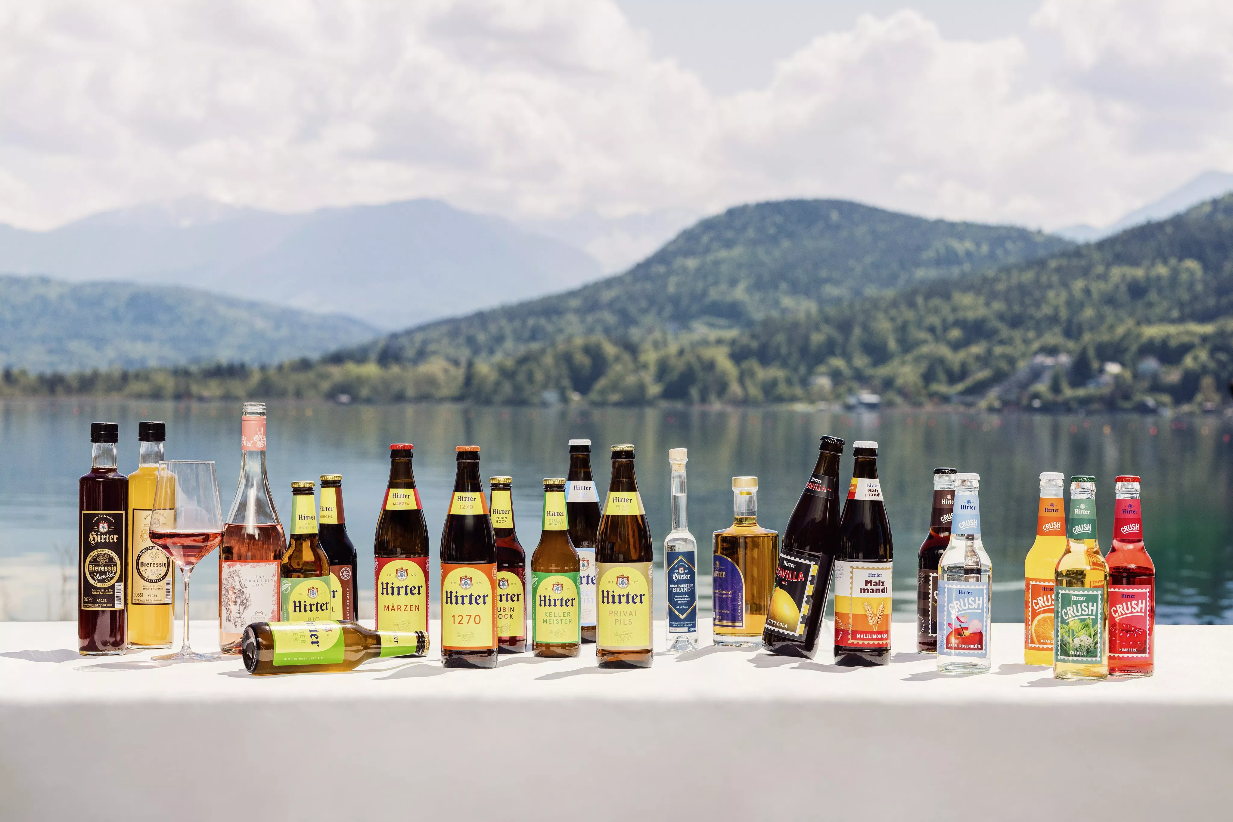 Das Sortiment der Privatbrauerei Hirt steht auf einem Tisch vor einer Bergkulisse.