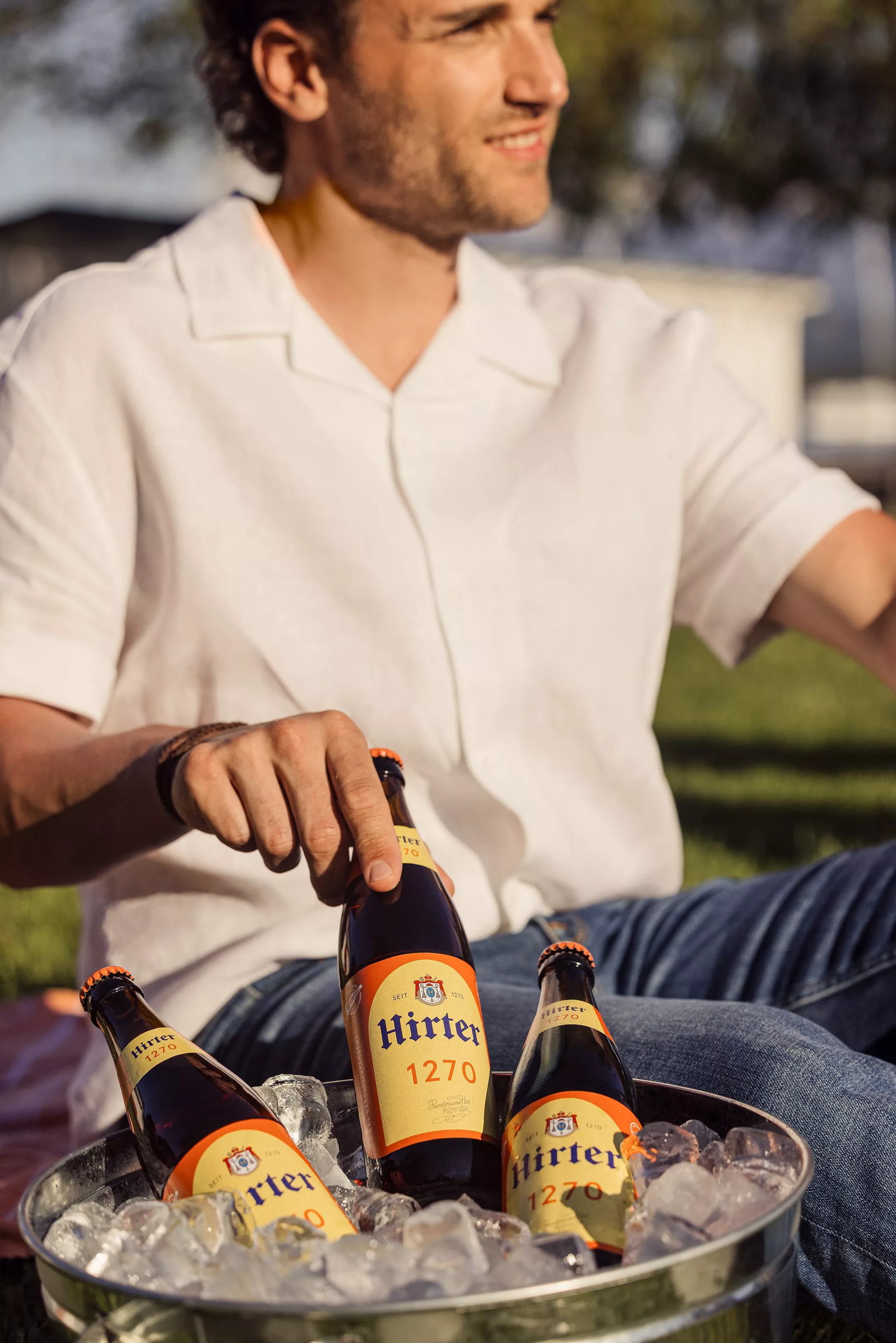 Ein Mann zieht eine Flasche Hirter 1270 aus einer Schale gefüllt mit Eiswürfel.